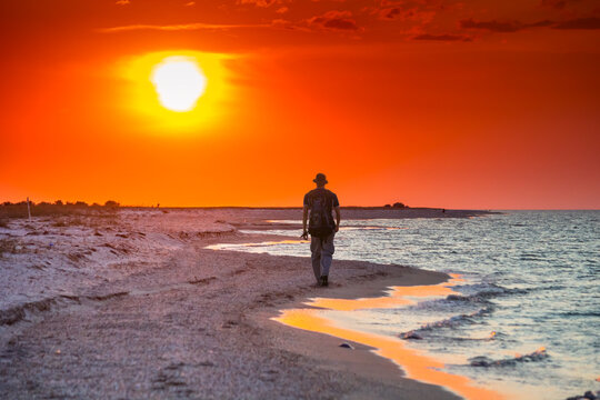 Tourist hike along the sea surf in the rays of the summer sun at sunset
