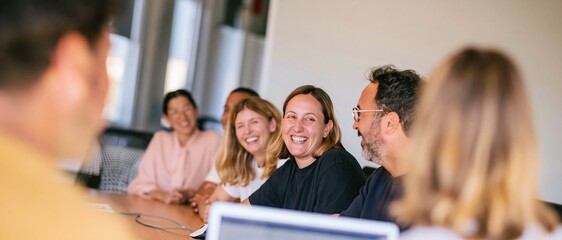 Obraz premium Diverse colleagues talking at a long wooden table in a bright loft office, a natural and engaged corporate scene with copy space for banners