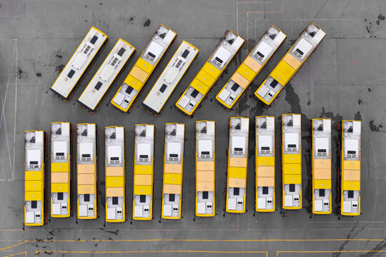 Aerial view of a fleet of yellow and white CNG buses parked in neat rows at a large depot in Poland.