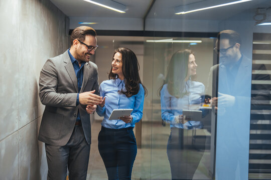 Business Colleagues Walking and Collaborating in Modern Office Corridor With Tablet and Smiles