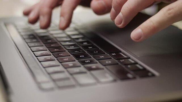 Close up macro of hands typing on laptop keyboard computer