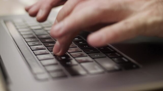 Close up macro of hands typing on laptop keyboard computer