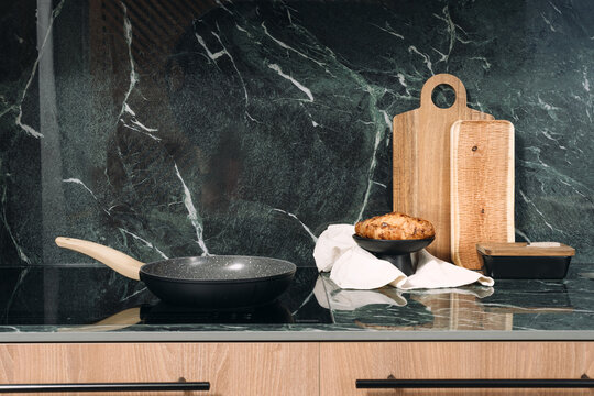 Induction hob with pan and baked goods on countertop in modern kitchen