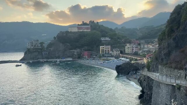 Scenic coastal view of Monterosso al Mare in the Cinque Terre region of Liguria, Italy, with the seaside village, rugged cliffs and Mediterranean coastline illuminated by dramatic late-day light. Mont