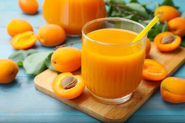 Apricot juice in glass and fresh fruits on light blue wooden table, closeup © New Africa