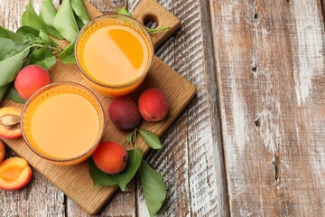 Glass of apricot juice, fresh fruits and leaves on wooden table, top view. Space for text © New Africa