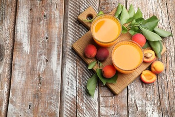 Glass of apricot juice, fresh fruits and leaves on wooden table, top view. Space for text © New Africa