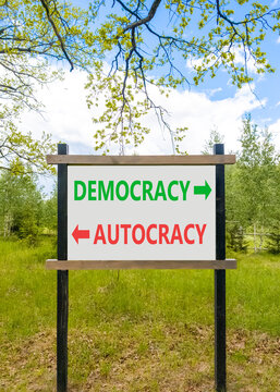 Democracy or autocracy words symbol. Concept words Democracy Autocracy on beautiful white road sign. Beautiful blue sky background. Business democracy autocracy concept. Copy space