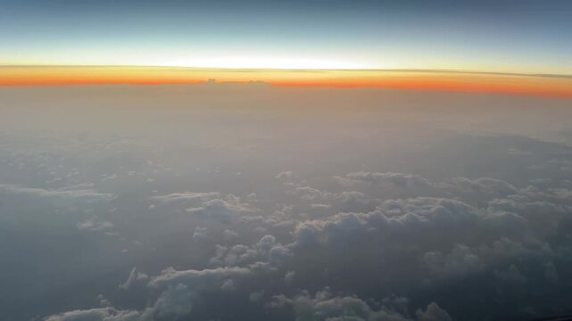 Pilot&rsquo;s point of view of a colorful sunrise over the North Atlantic Ocean from cruising altitude, with a glowing horizon and expansive cloud layers below.
