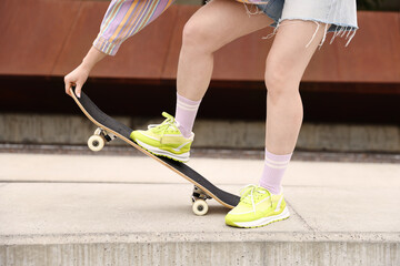 Woman riding skateboard on city street, closeup © New Africa