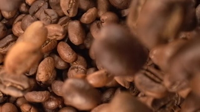 Roasted coffee beans falling in super slow motion macro top view