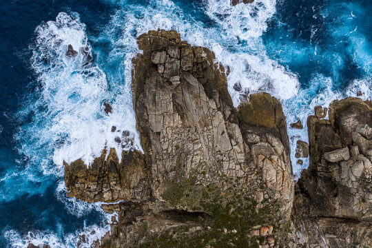 Aerial view of the rugged granite coastline and blowholes at Torndirrup National Park with crashing waves and white sea foam against the dark rocks in Torndirrup, Western Australia, Australia.
