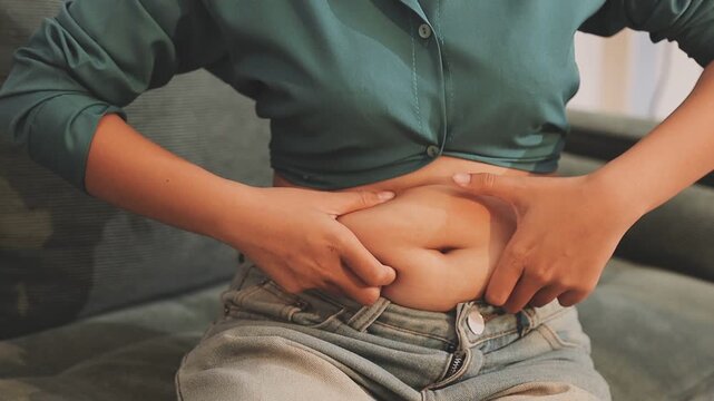 Overweight woman body with hands touching belly fat