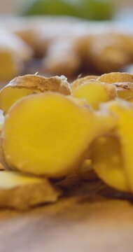 Macro close-up of sliced ginger root on a wooden surface with shallow depth of field, representing fresh spice, natural wellness, and healthy cooking. Vertical.