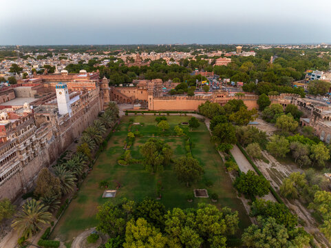 Aerial view of the historic Junagarh Fort featuring intricate sandstone architecture and expansive green courtyards within the city of Bikaner, Rajasthan, India.