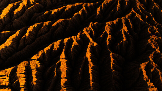 Aerial view of the rugged, golden-lit ridges of the Ak-Say Valley at sunset, showcasing dramatic shadows and textures in the mountain landscape, At-Bashi District, Naryn Region, Kyrgyzstan.