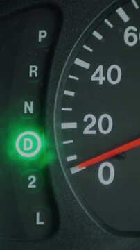 Close-up of an automatic transmission gear indicator switching between modes on a car dashboard. Vehicle controls, driving, automotive technology, and transportation concept. Vertical.