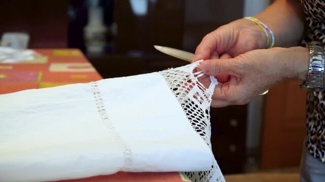 A woman is doing sewing work with scissors and fabric.