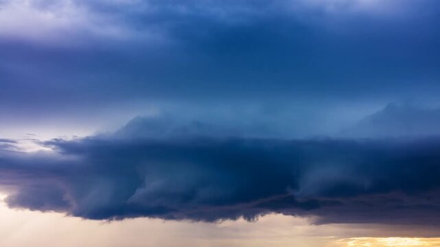 Time lapse panning shot of storm clouds forming and rolling across flat horizon over open plains at sunset dusk