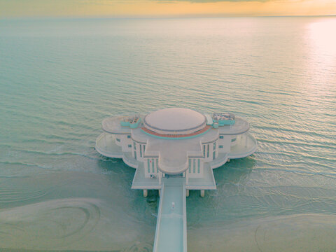 Aerial view of the Rotonda a Mare, a unique circular building extending into the Adriatic Sea at sunset, with calm waters and a sandy beach in Senigallia, Marche, Italy.