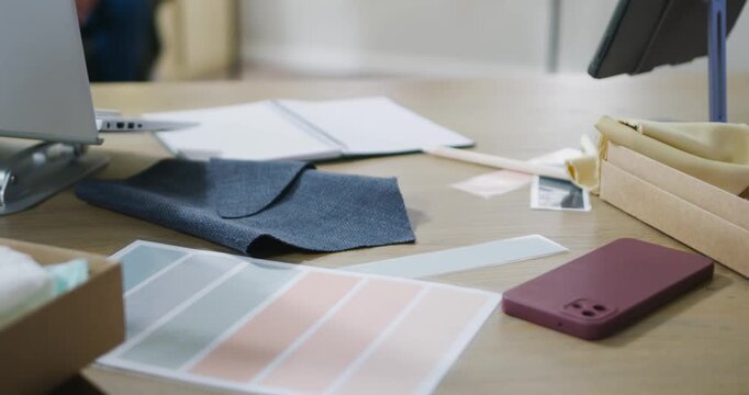 Camera is shifting laterally and refocusing, bringing fabric swatch and maroon phone into focus