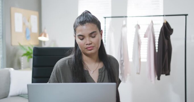 Spotting paper African American woman in olive blouse in studio reaching document, verifying laptop