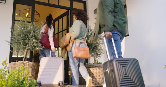African American traveling companions led by woman signaling on phone, pulling suitcases to visit
