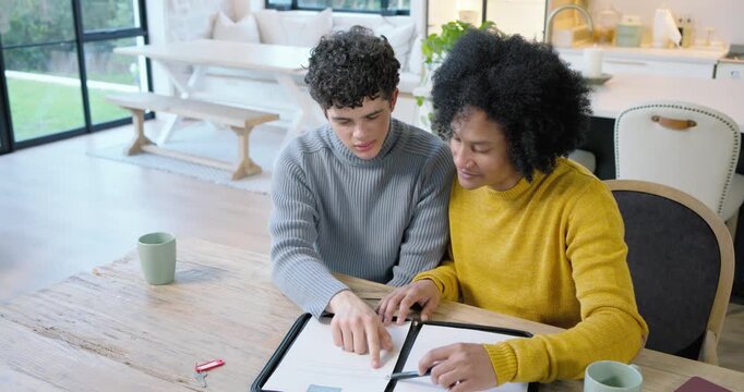 Diverse male pair with teen reviewing binder at table, signing hugging celebrating home red key fob