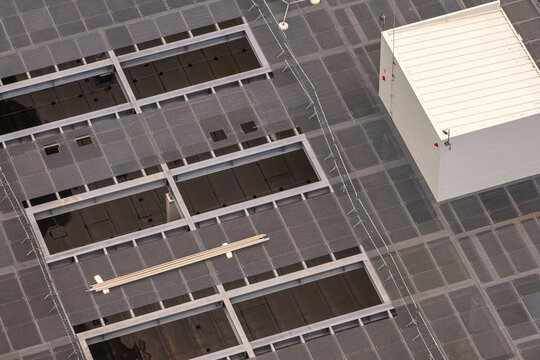 Aerial view of the roof of an AI data center under construction featuring metal grating, rectangular openings, and a white equipment housing unit in Poland.