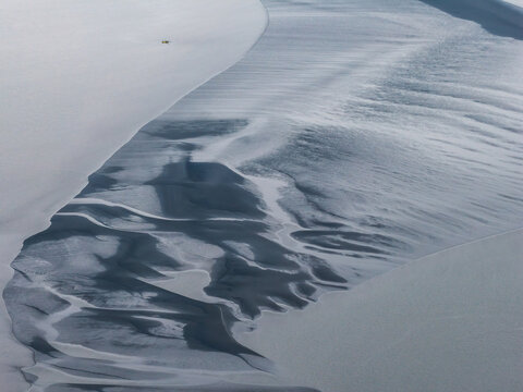 Aerial view of the tidal flats and intricate water channels at Beluga Point with textured sandbars and silt deposits in Anchorage, Alaska, United States.
