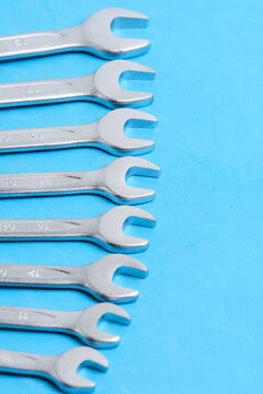 Close up open end wrenches lined up vertically along edge vibrant blue background.