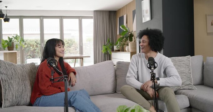 African American cohosts laughing and recording podcast with male joining on sofa by mics