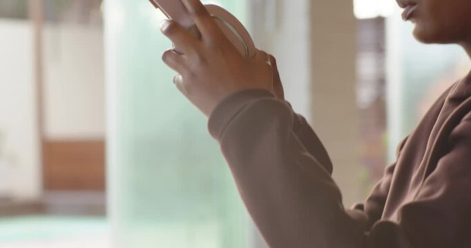 African American woman on mat with band seeing cell, adjusting pink headphones to listen