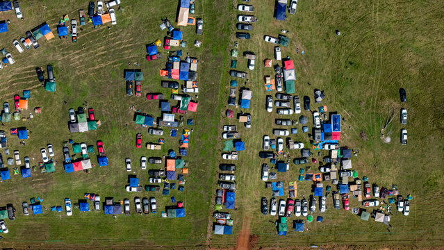 Aerial view of Rally Paraguay 2026 with numerous cars parked in organized rows on a grassy field, featuring various tents and spectators in Nueva Alborada, Itapua Department, Paraguay.