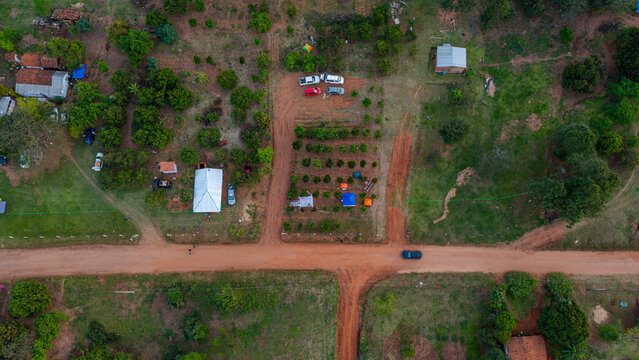 Aerial view of rural landscape with dirt roads, scattered houses, fruit trees, and parked vehicles in Nueva Alborada, Itapua Department, Paraguay.