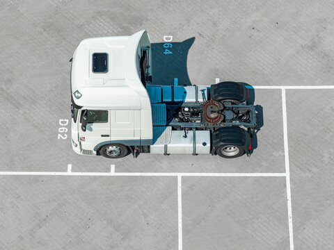 Aerial view of a white semi-truck tractor unit parked in a paved lot with marked parking spaces in Poland.