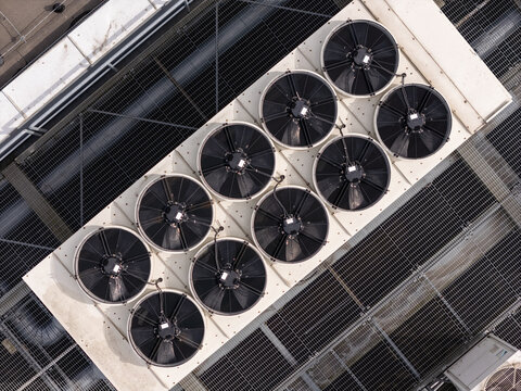 Aerial view of industrial cooling fans arranged in a grid on a rooftop with metal grating in Gdansk, Poland.