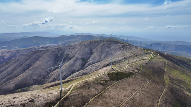 Aerial view of a wind farm with multiple wind turbines across a mountainous landscape, representing renewable energy and clean power in Lisbon, Lisbon, Portugal.