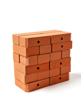 Stack of red perforated clay bricks on a white background