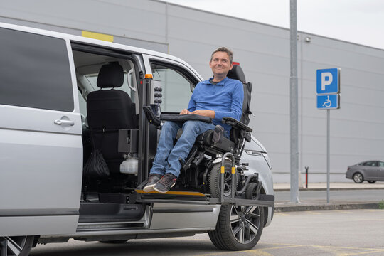 A man with a disability operates a wheelchair accessible car with lift in a parking lot. He looks confident and independent in his vehicle.