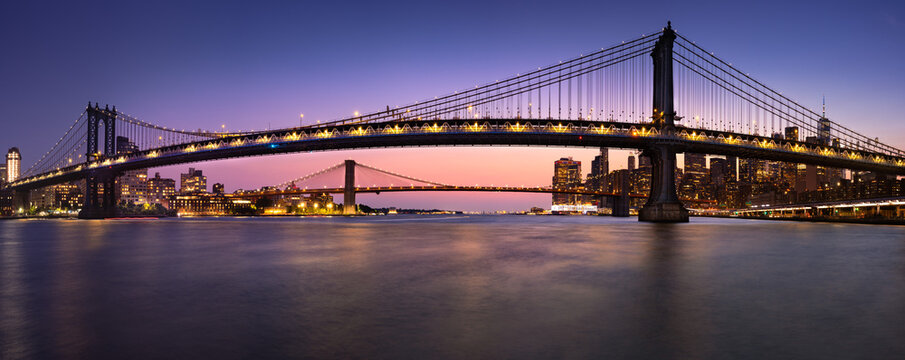 UNITED STATES, NEW YORK CITY, LOWER EAST SIDE. MANHATTAN BRIDGE AND BROOKLYN BRIDGE AND EAST RIVER IN EVENING. VIEW OF DUMBO IN BROOKLYN AND LOWER MANHATTAN