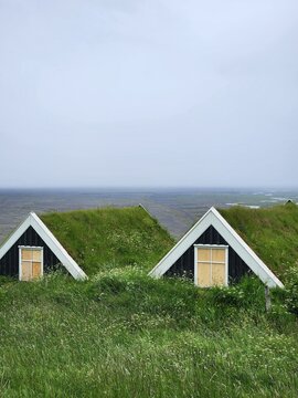 Traditional Icelandic turf houses with black wooden gables and grass roofs overlooking vast landscape in Iceland
