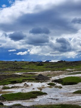 Icelandic tundra landscape with geothermal ground turf house and glacier under dramatic cloudy sky