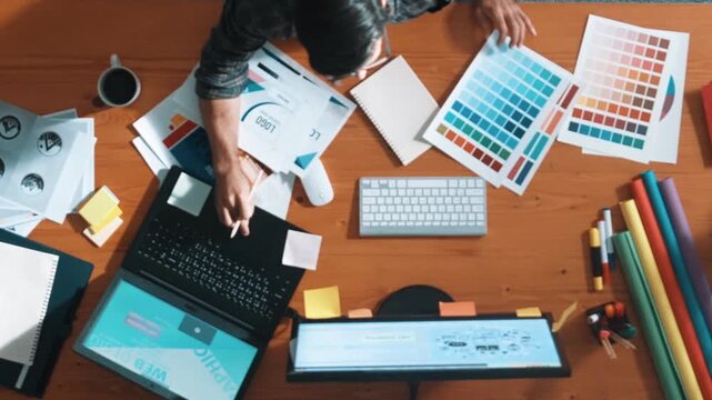 Top view of smart businessman hand choosing color palettes while designing logo graphic. Aerial view of professional interior designer design and select color theme by using color palettes. Symposium.