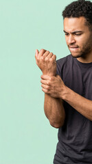 Naklejka premium Man suffering from wrist pain holding his arm. Young male in agony after injury to hand. Chronic discomfort, medical problem, health issue. Isolated on green background with copy space.