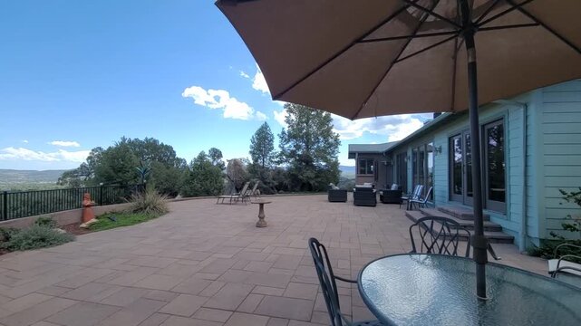 Sunlit patio overlook with umbrella glass table lounge seating distant mountains