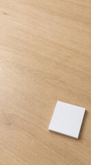 Fototapeta premium Blank square white memo pad on light oak table