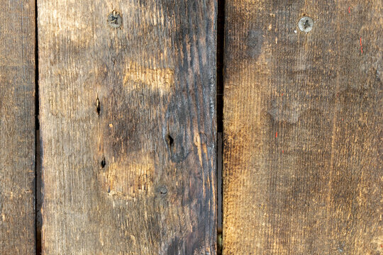 Close-up of old wooden boards with dark weathering, visible grain, nail marks and natural wear forming a rustic timber texture.