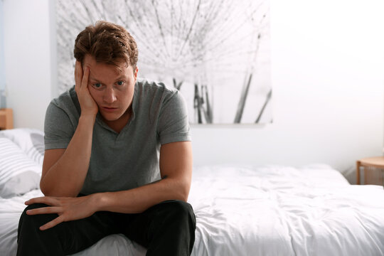 Stressed man suffering on bed at home. Space for text