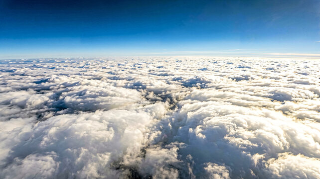 Aerial view of fluffy white clouds under a clear blue sky.